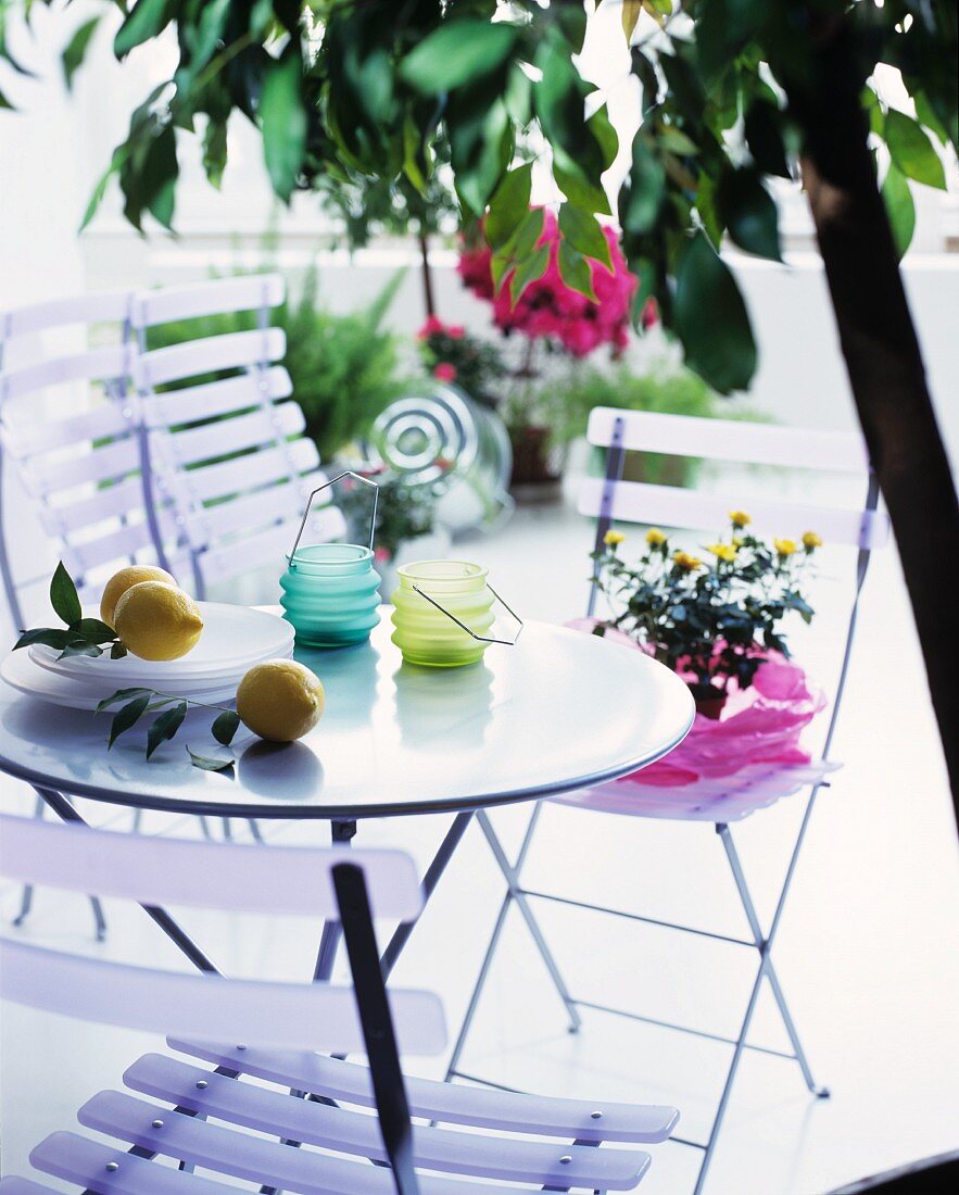 Windlichter und Zitronen auf Gartentisch mit Klappstühlen