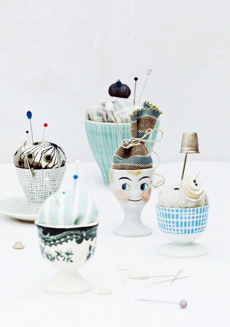Unusual pincushions in painted eggcups with fabric 'hats'