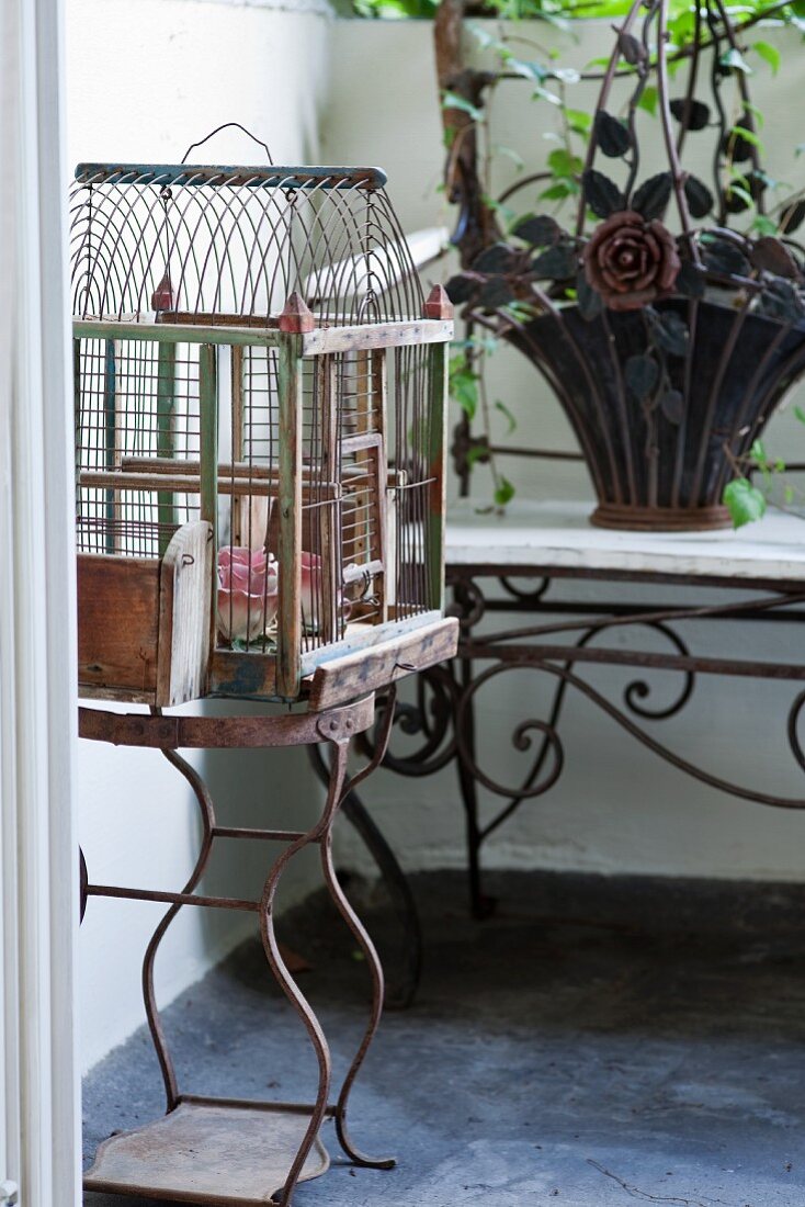 Birdcage on rusty stand on balcony