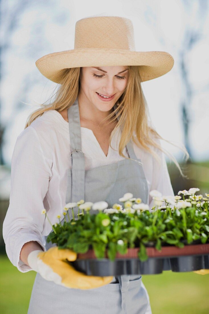 Frau hält Tablett mit Frühlingsblumen