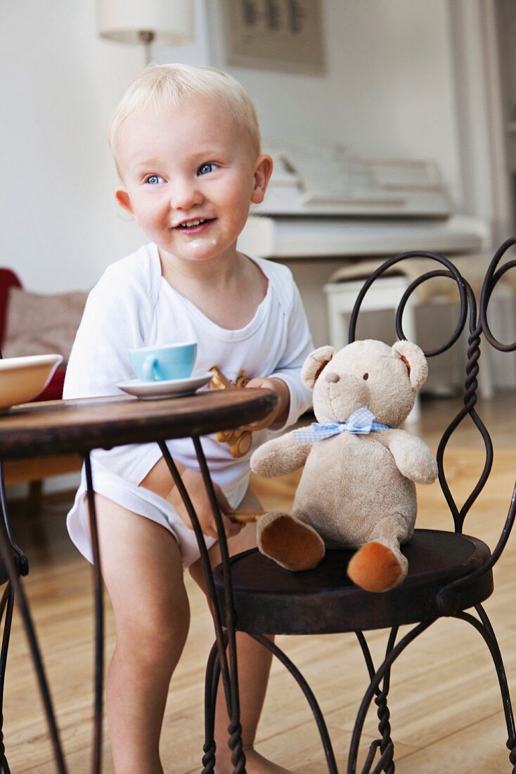Kleiner Junge bei der Teeparty mit seinem Teddy