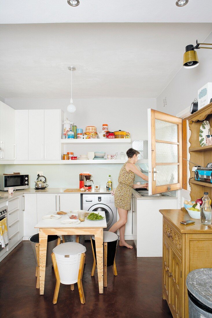 Essplatz mit Hocker in funktionaler Küche, im Hintergrund Frau