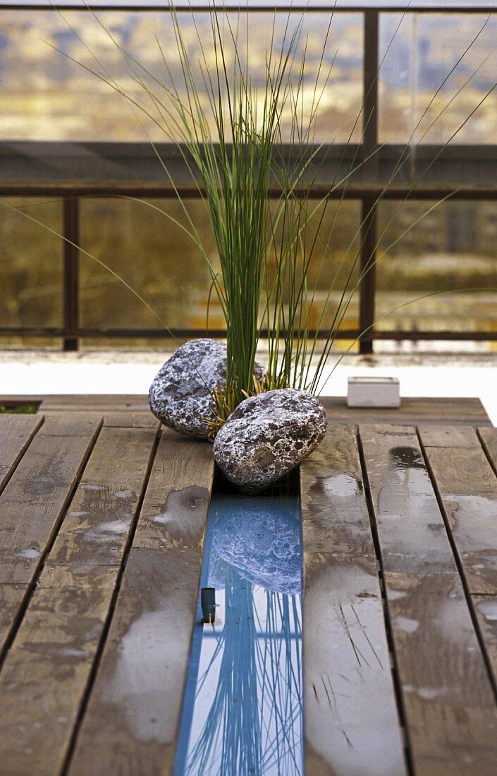 Holzpodest auf Terrrasse mit Wasserpflanze & Steinen dekoriert
