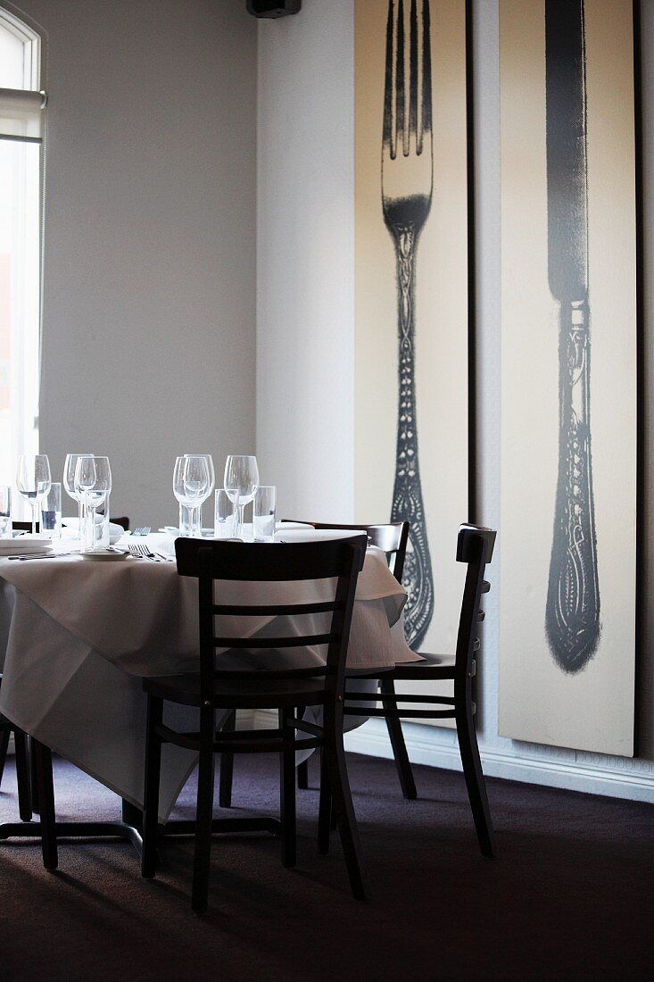 Gedeckter Restauranttisch neben großen Wandbildern
