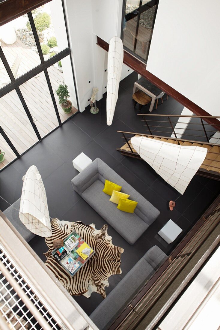 Modernes Wohnzimmer mit schwarzem Fliesenboden und raumhoher Fensterfront aus der Vogelperspektive