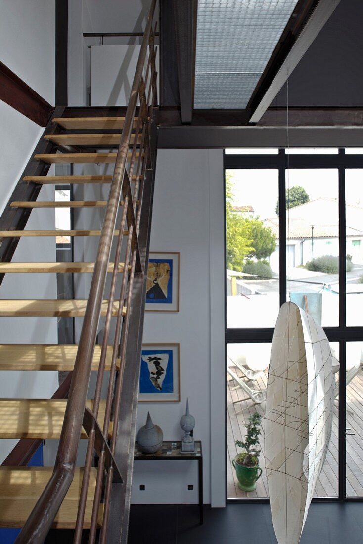 Eine Stahltreppe mit Holzstufen im Fabrikstil führt vom Wohnzimmer mit großer Fensterfront auf die Galerie