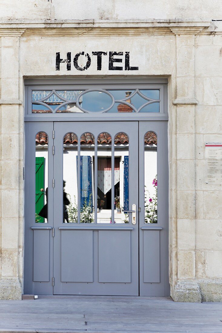 Mirrored entrance door to a hotel with a historic stone facade