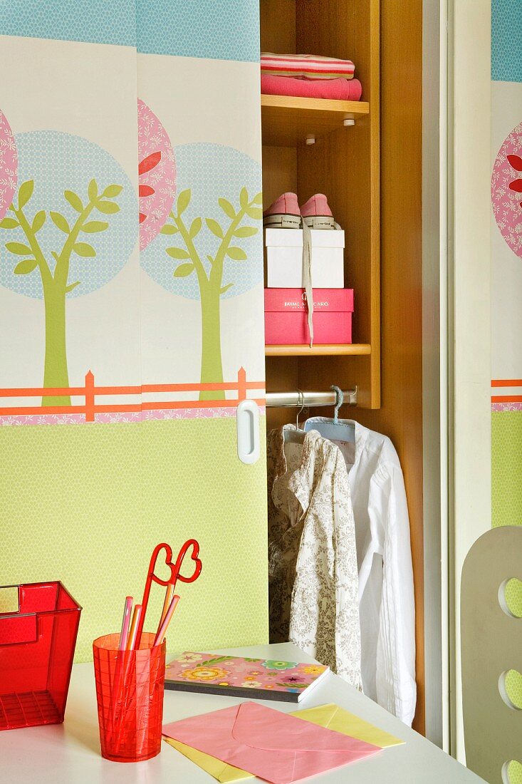 Pastellfarbene Baum-Illustrationen auf den halboffenen Schiebetüren eines Kleiderschranks in Mädchenzimmer