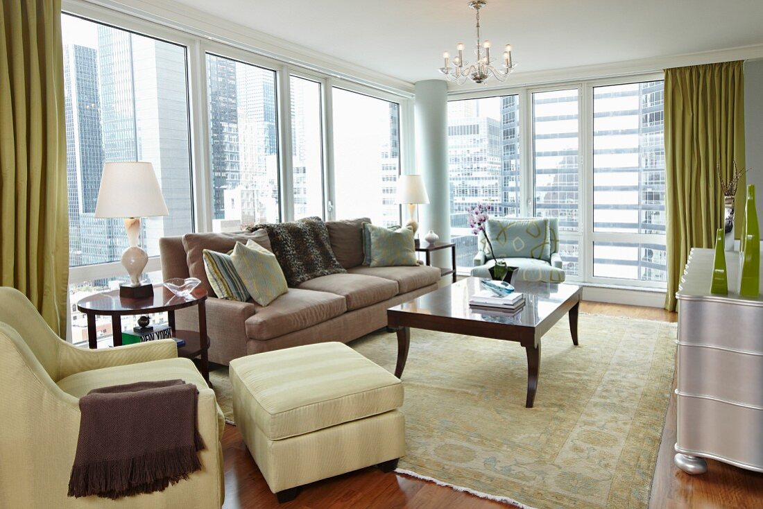 Elegante Stilmöbel in übereck verglastem Wohnzimmer mit Blick auf die Skyline
