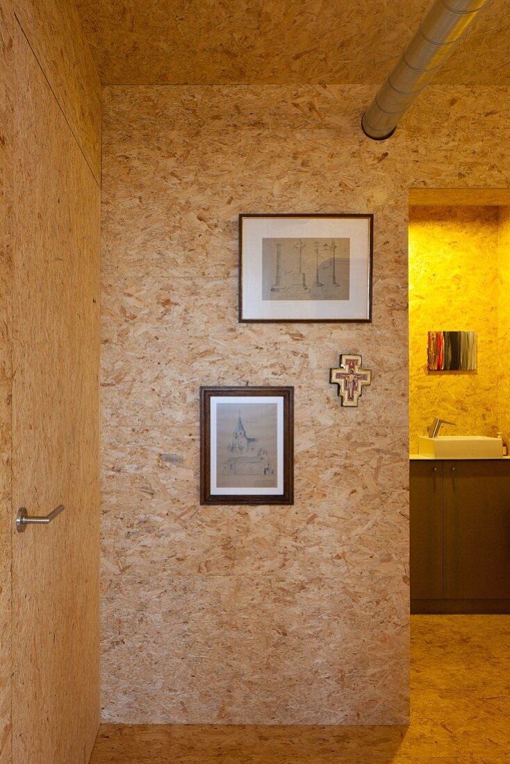 Wohnraum mit Spanplattenausbau und Blick durch offenen Durchgang auf Waschtisch