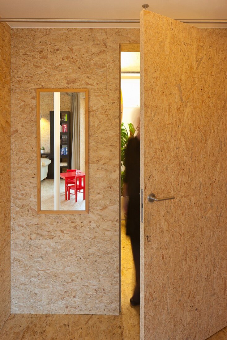 Zimmer aus Spanplatten mit groben Holzschnipseln und offenstehender Tür
