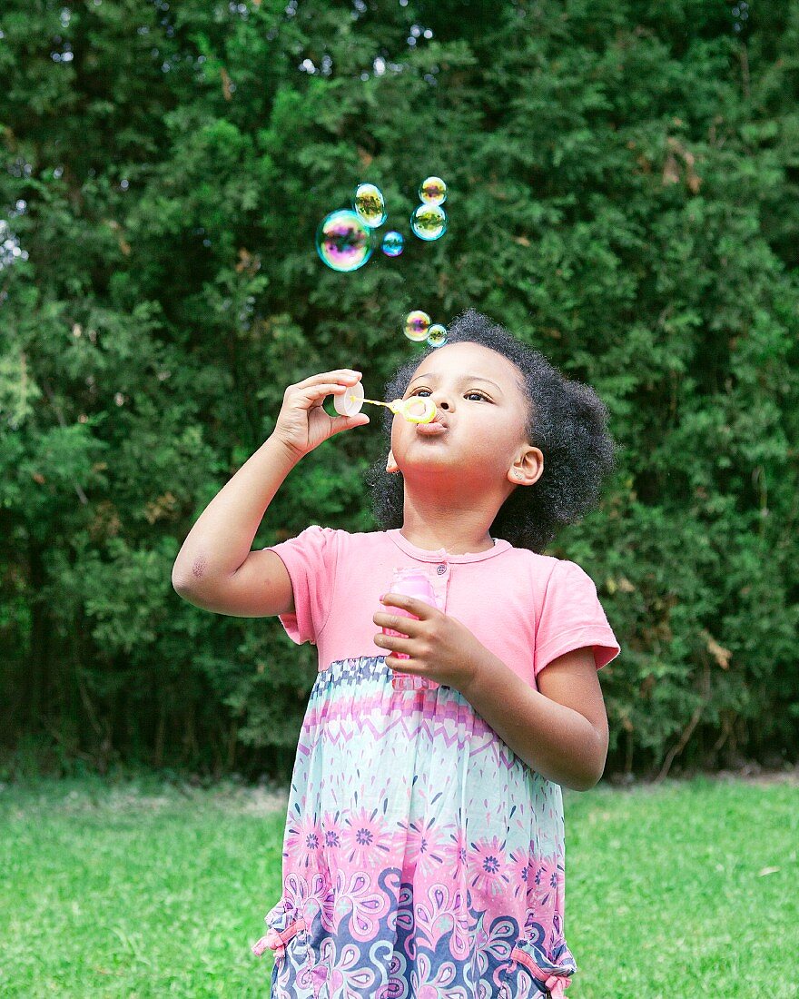 Dark haired girl blowing soap bubbles