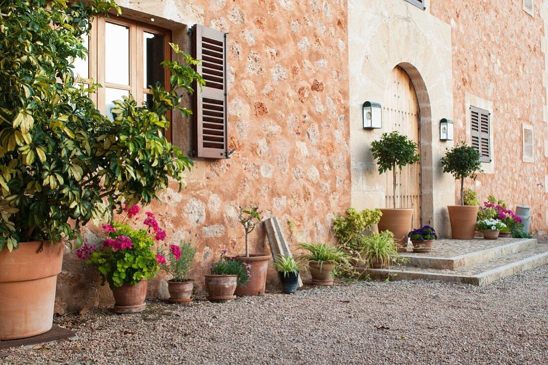 Outside view of entrance area of traditional, Spanish Finca with stone facade and potted plants