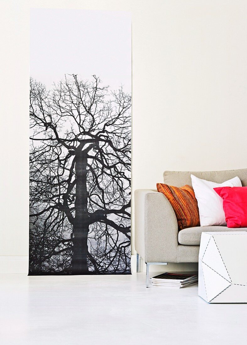 Large, narrow picture of tree next to sofa