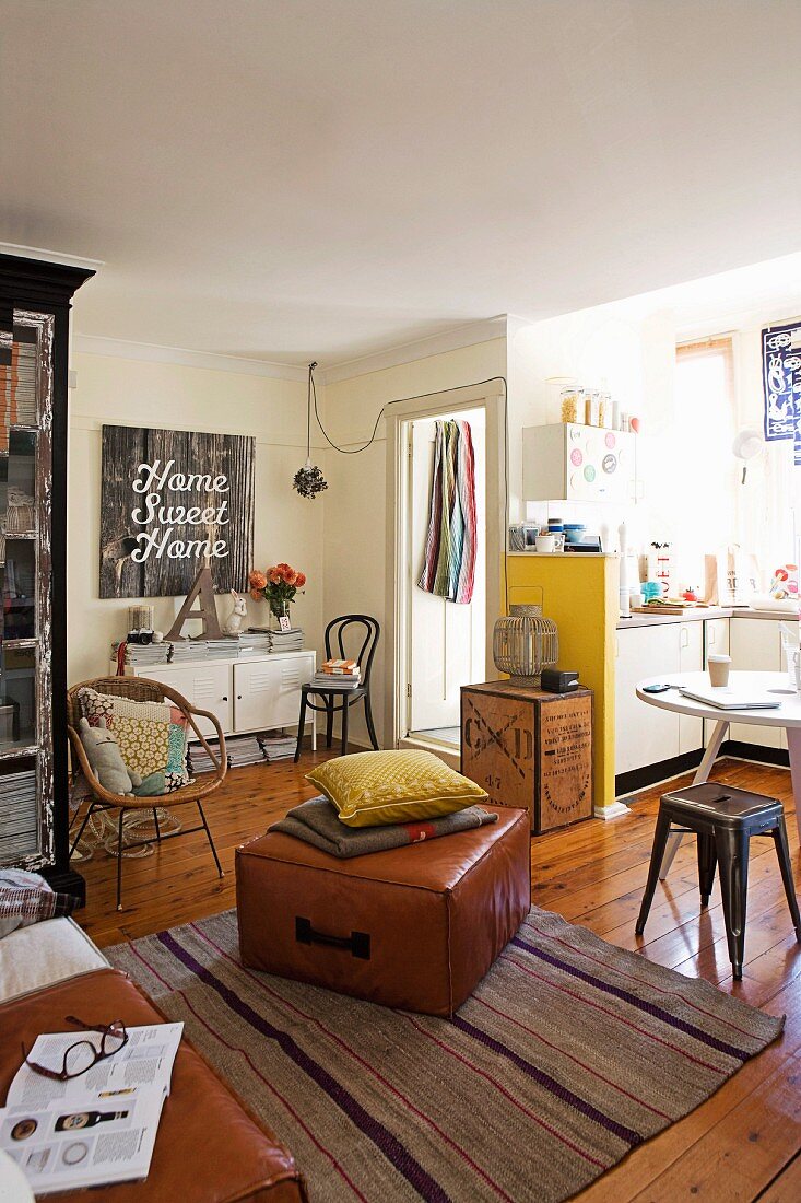 Offener Wohnraum und Küchennische mit gesammelten Vintage-Möbeln verschiedener Stilrichtungen auf Landhausdielen