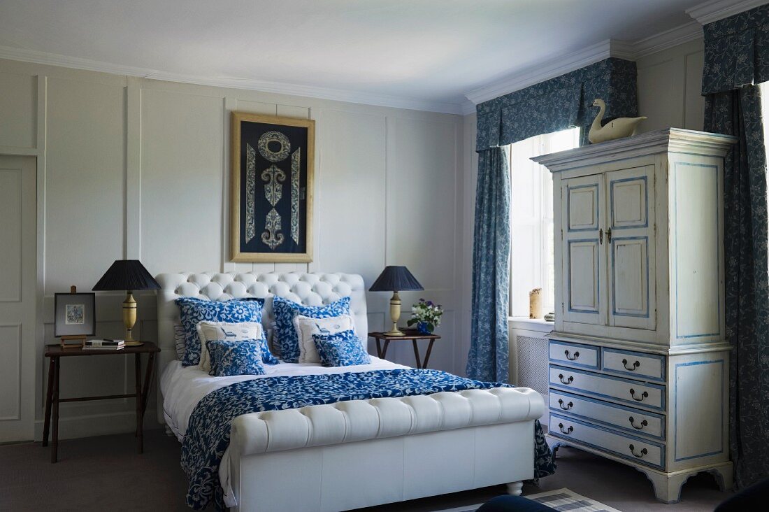 Doppelbett mit weißem, gepolstertem Kopfteil in traditionellem Schlafzimmer mit weiss-blauen Farbakzenten