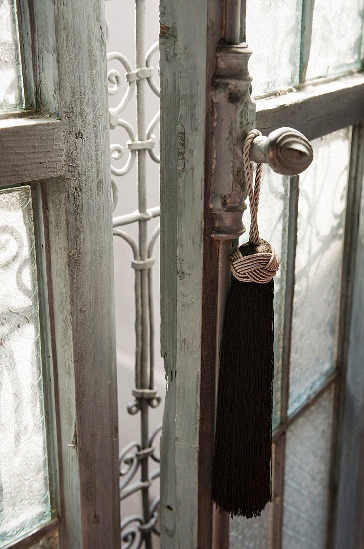 Elegante Troddel an Fensterolive eines alten Fensters mit weißem Metallgitter