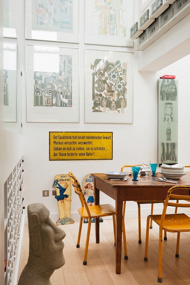 Holztisch mit gelben Metallstühlen, Schild mit Bazon Brock Zitat und Werke von Eduardo Paolozzi in der Küche