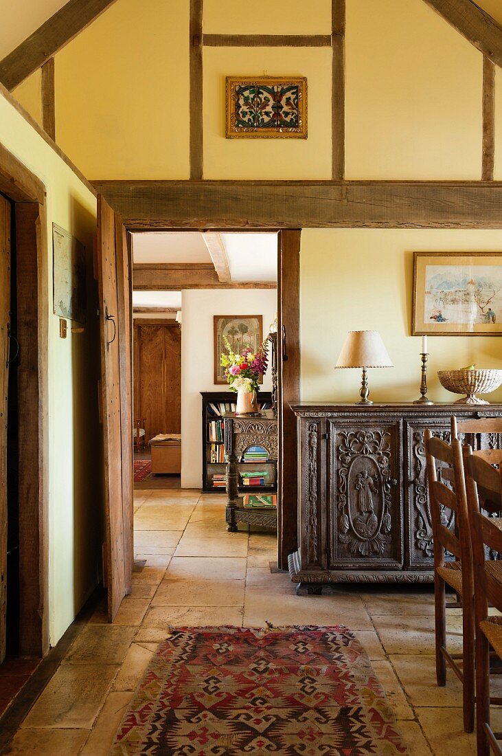 View from dining area in foyer of simple English country house with antique furniture and exposed timber structure