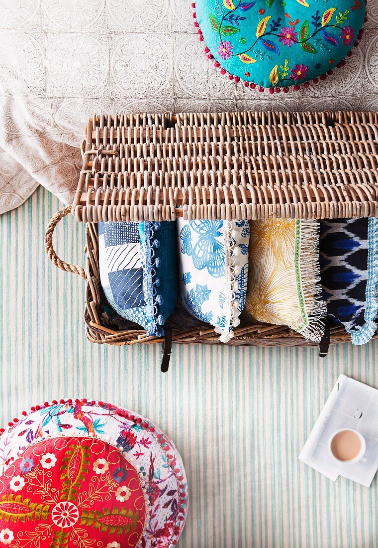 Pillow madness - ethnic cushion next to a basket with pillows on a striped surface