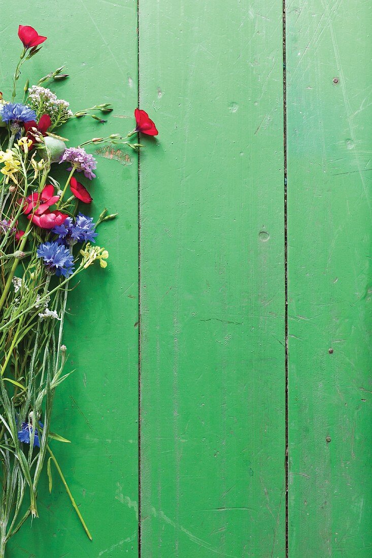 Bunte Wiesenblumen auf grünem Holztisch