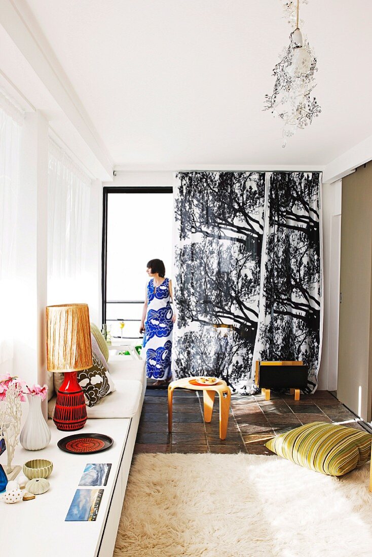 Curtain with black and white tree motif; collection of vintage objet on sideboard in foreground