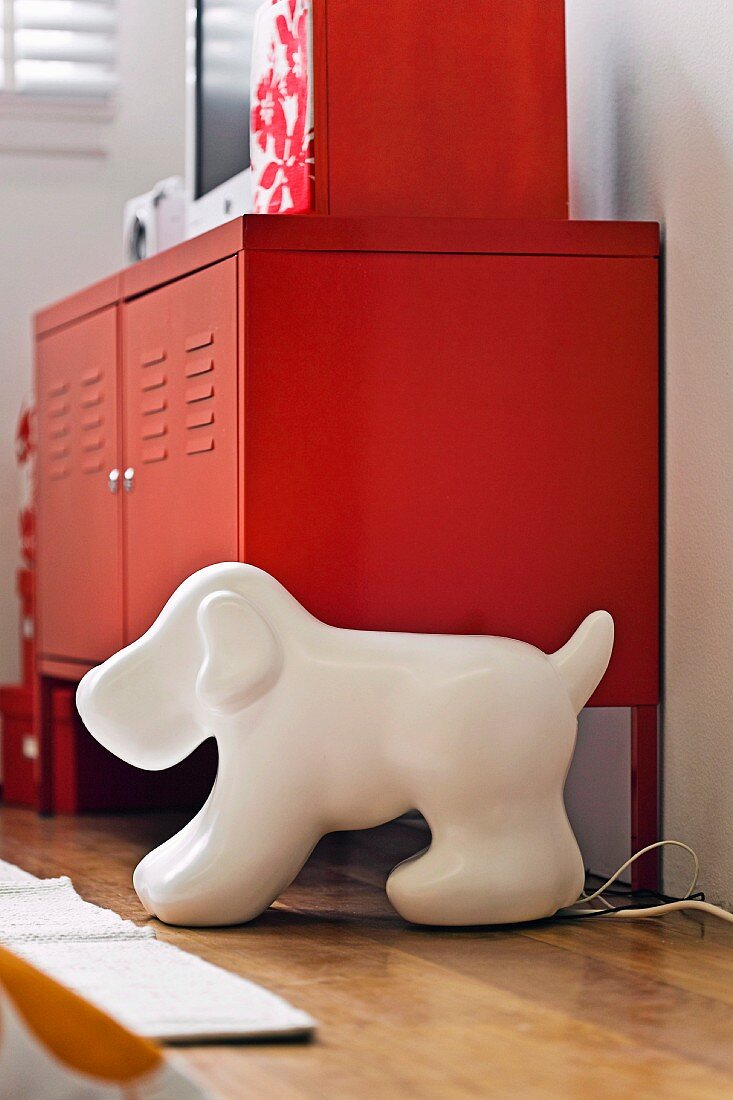 Red metal sideboard behind lamp in shape of stylised dog