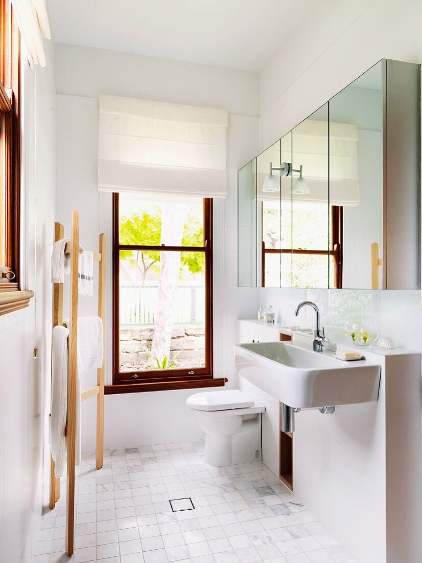 Modernes, schmales Badezimmer mit ausladendem Spiegelschrank und Fenster