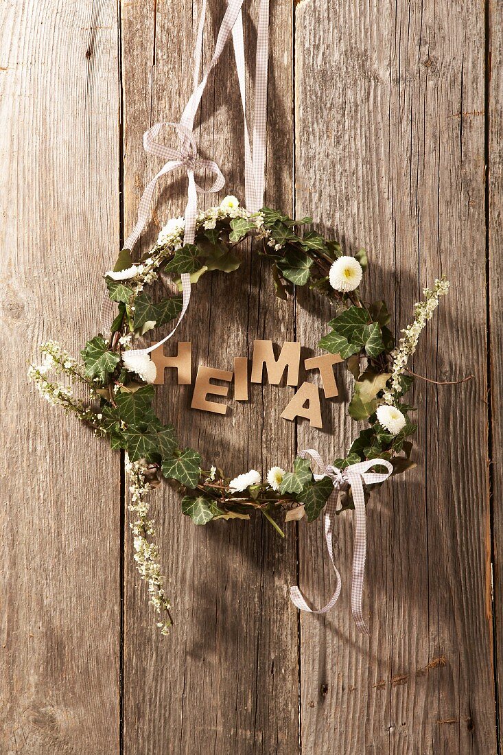 Wreath made of ivy and daisies and the word 'home'
