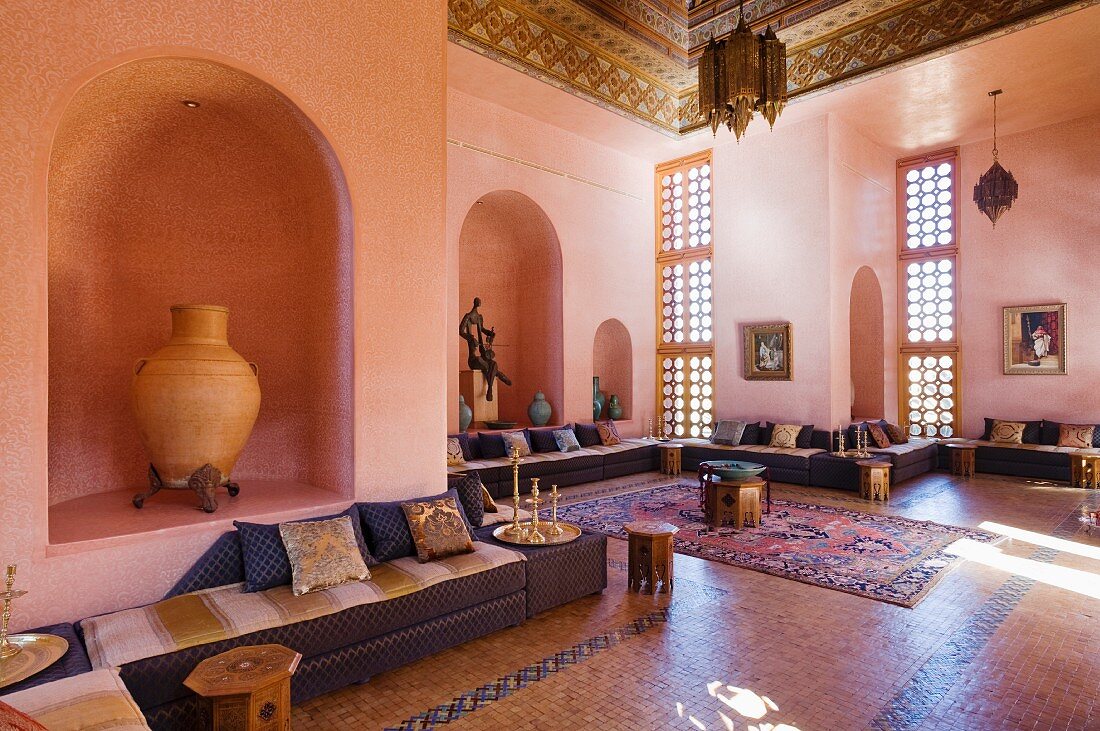 A salon marocain with velvet covered seating around walls and a Fez-work carved and painted ceiling