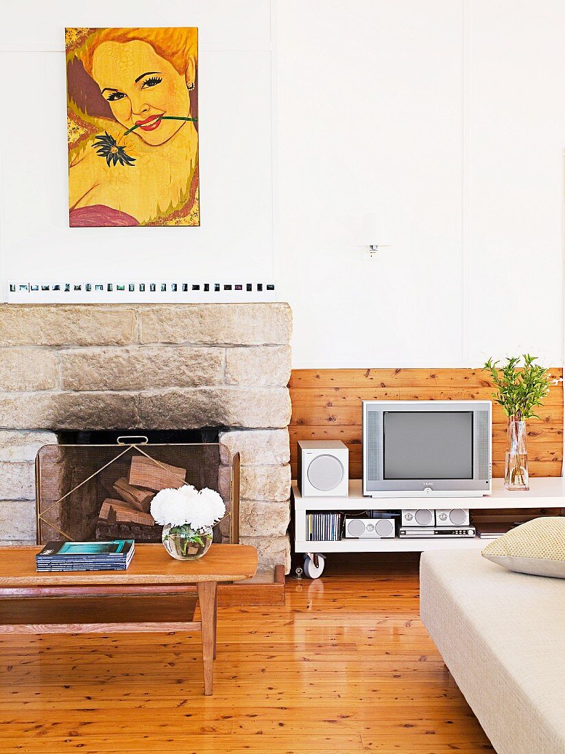 Sooty stone fireplace in pleasant, bright living room with wooden boards on wall and floor