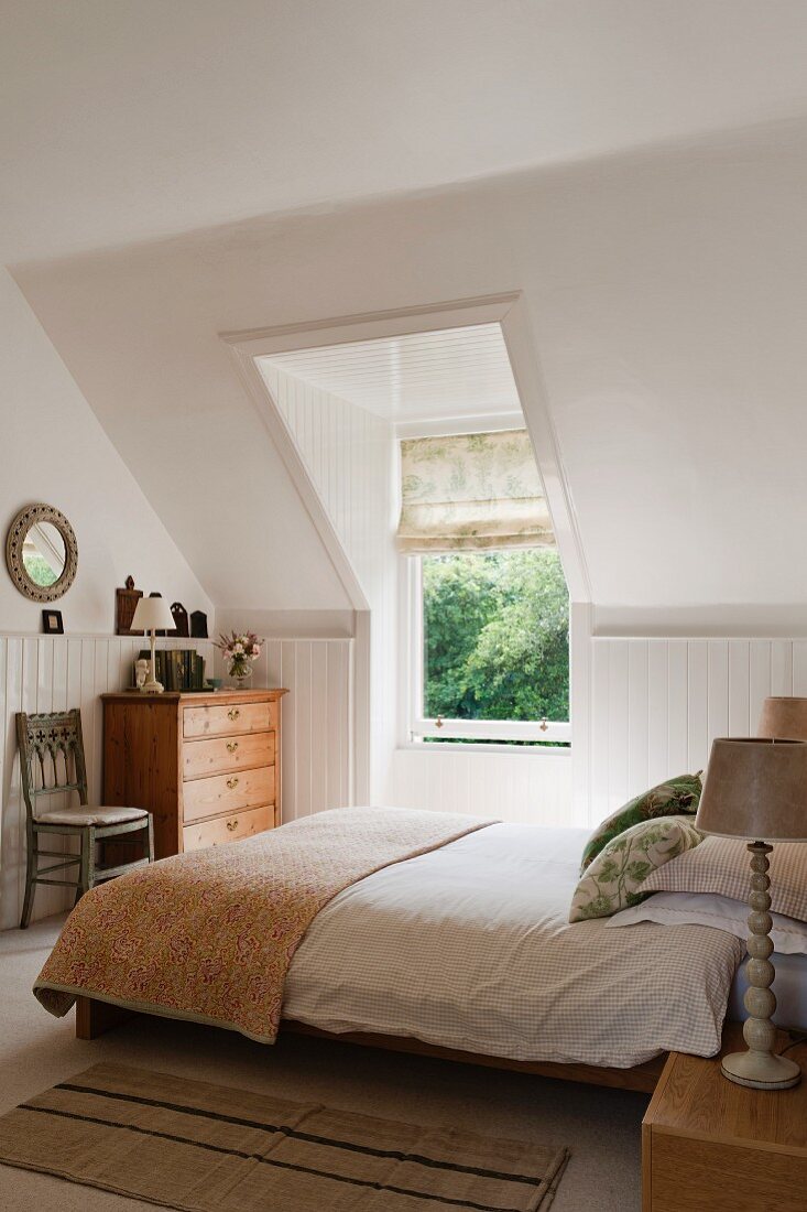White double bedroom with sloping walls and Laura Ashley lamps