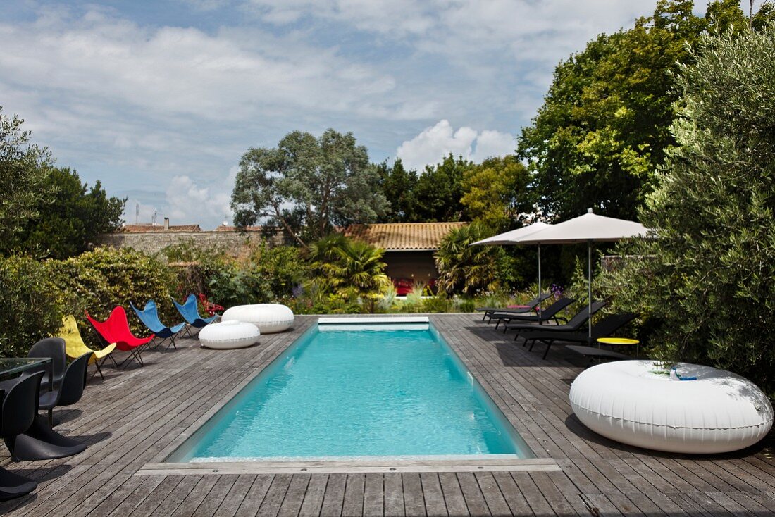 Bunte Schmetterlingsstühle und Terrassenmöbel auf großer Holzterrasse mit Pool