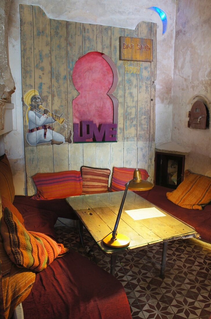 Wohnecke im orientalischen Stil mit Tischlampe auf dem Holztisch und Steinmosaikfußboden