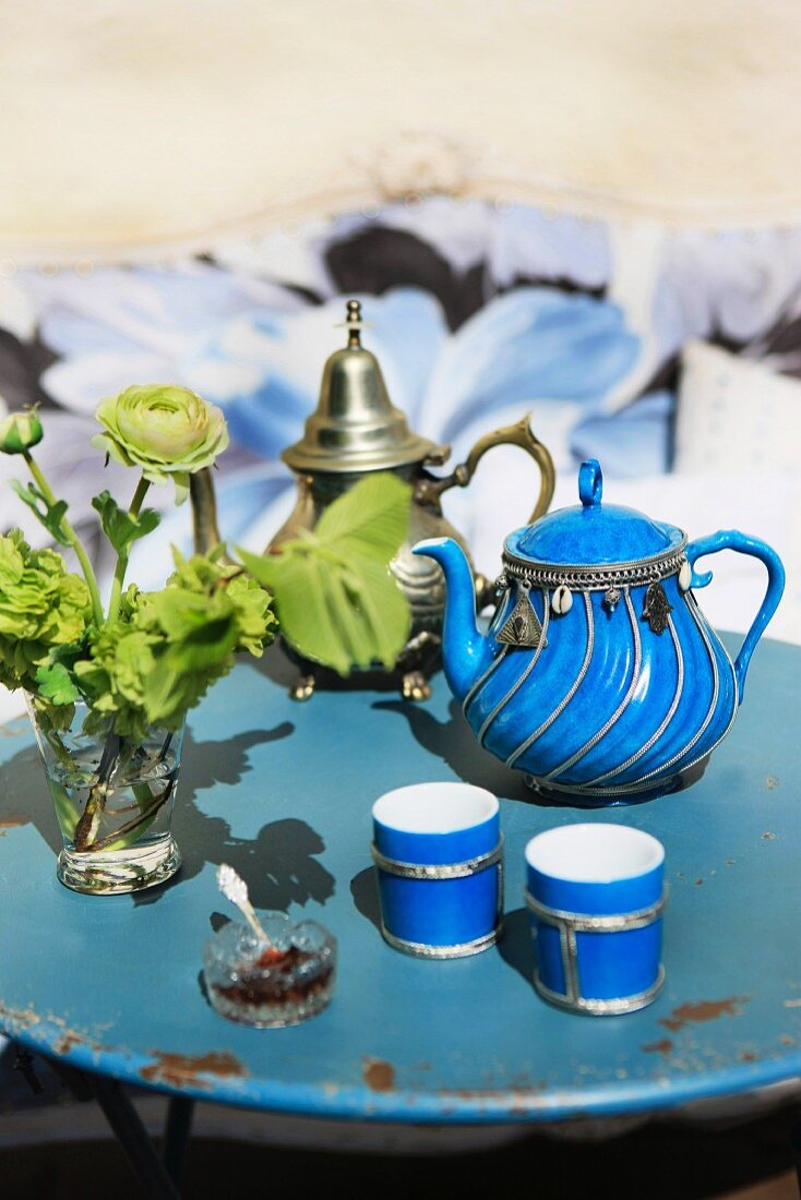 Kanne aus silberverziertem, blauem Porzellan mit passenden Teebechern auf altem, rundem Gartentisch aus Metall