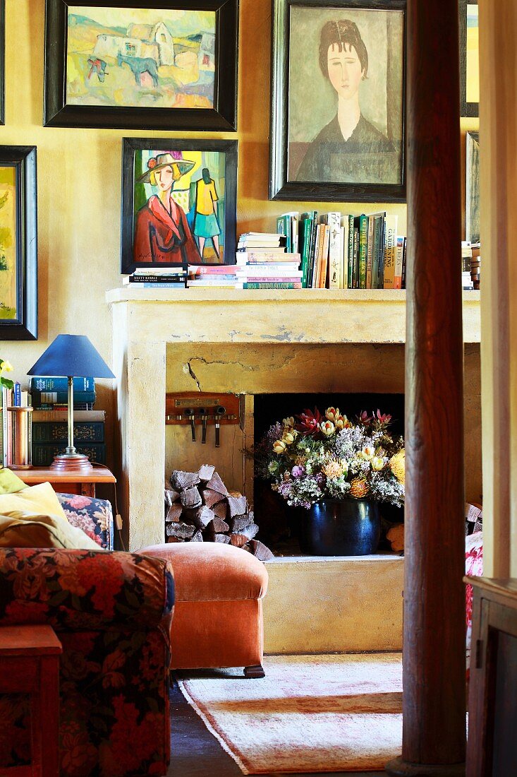 Collection of paintings in living room of old country house - modern paintings above open fireplace on wall painted yellow