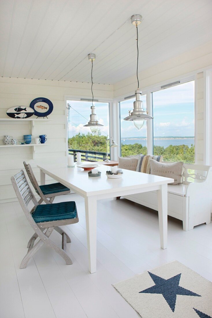 Weisser Esstisch und Klappstühle aus Holz am Fenster mit Ausblick