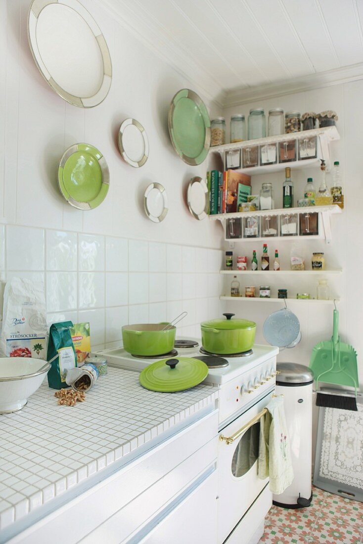 Sunny kitchen with retro cooker and collection of white and green china plates on wall