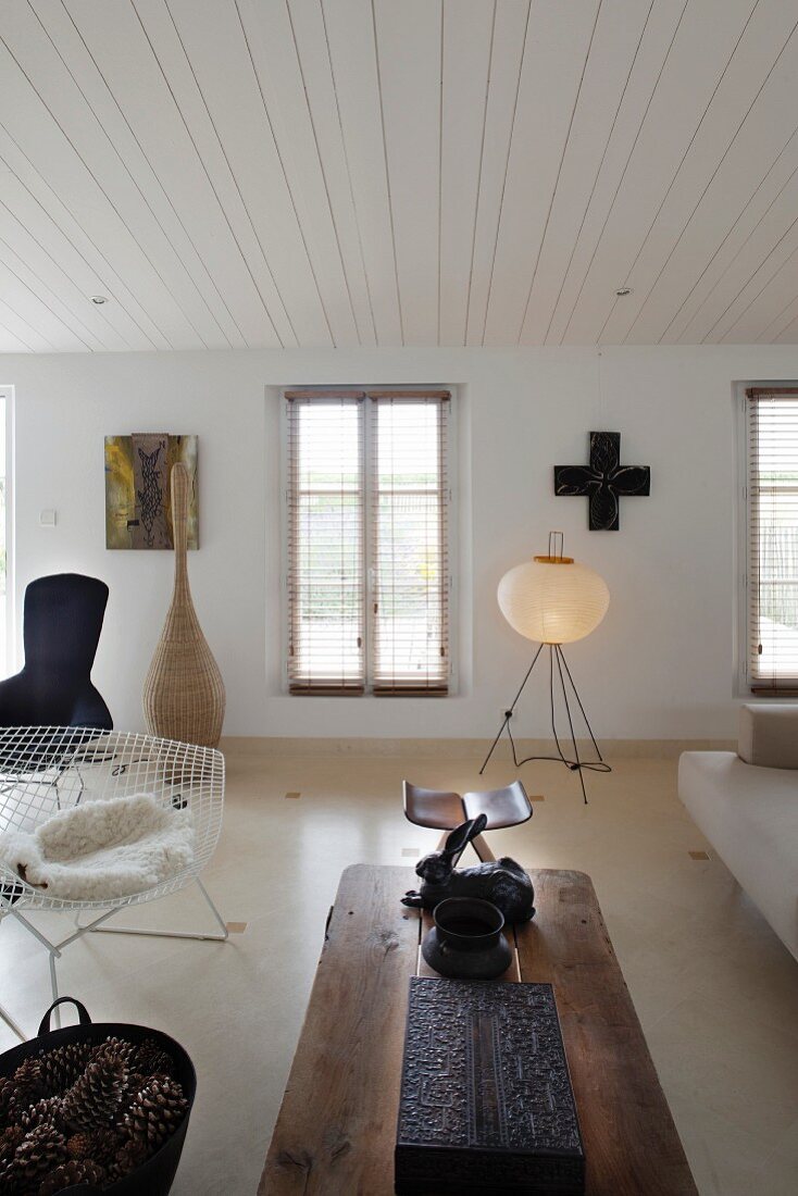 Wohnraum in eklektizistischem Stil - Stuhl aus 50er Jahren und rustikaler Couchtisch vor zeitgenössischer Stehlampe