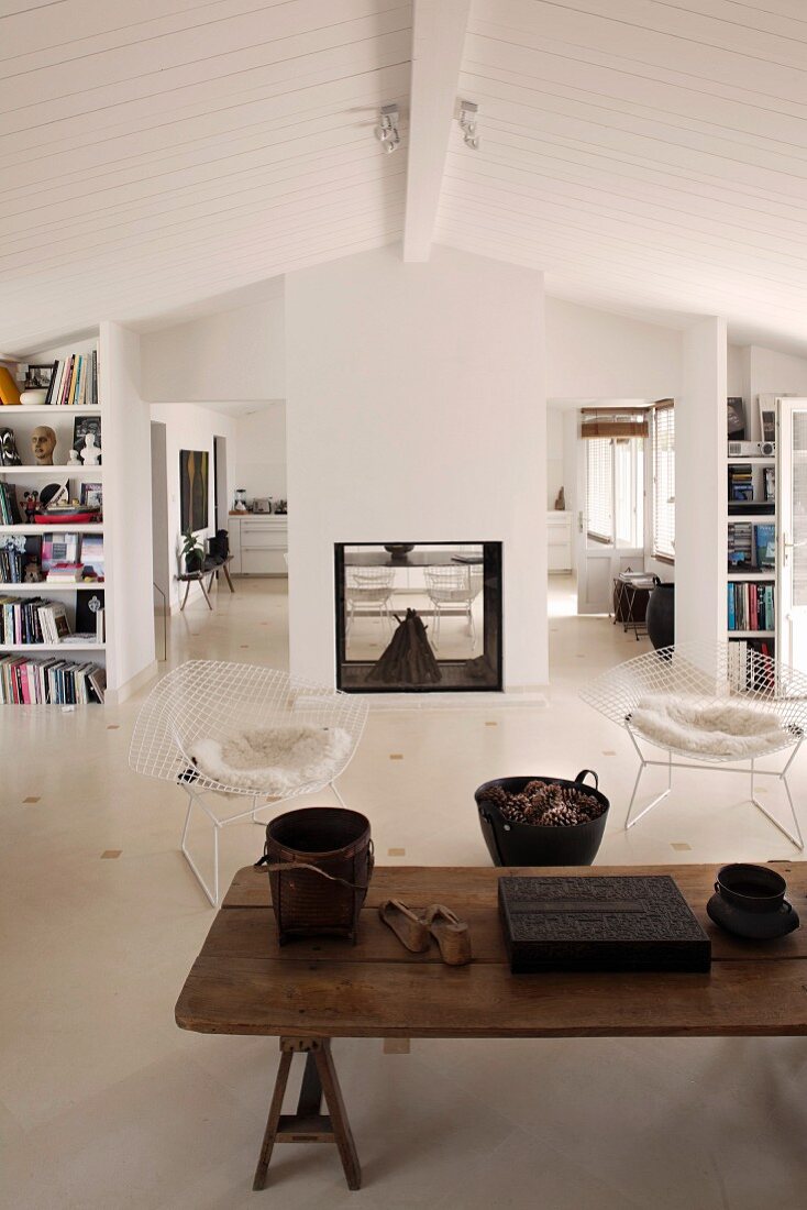 Rustic wooden coffee table and classic chairs in a simple living room with white wood ceiling