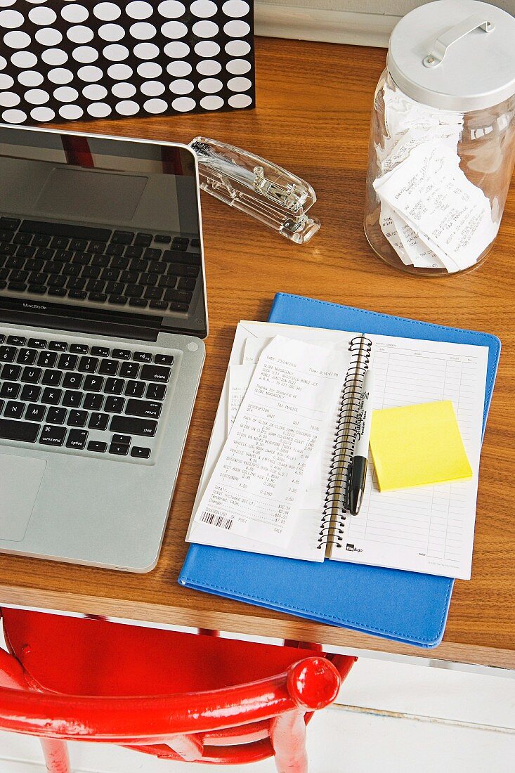 Schreibtisch mit Laptop neben offenen Notizen