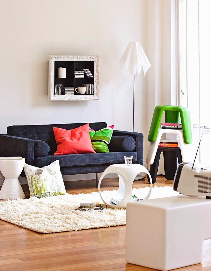 Freundliches Wohnzimmer mit farbigen Stapelhockern und Beistellelementen aus weißem Kunststoff