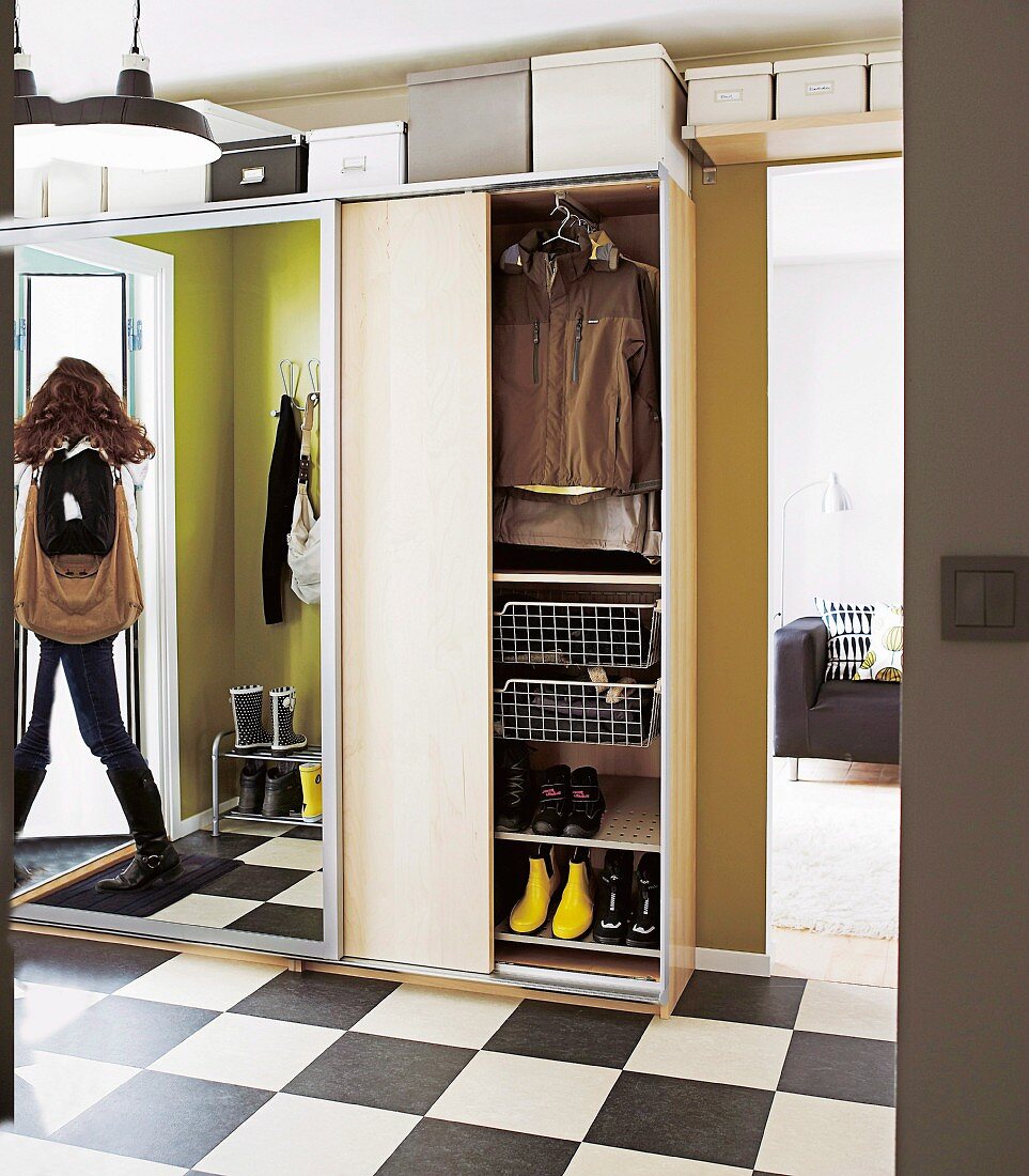 Viel Stauraum in der modernen Diele durch Garderobenschrank mit Spiegelschiebetür; Frau in Spiegel reflektiert