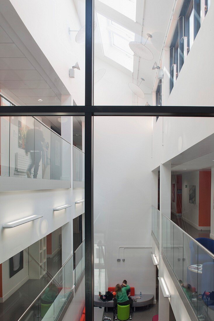 Blick durch das verglaste Treppenhaus ins Atrium einer modern gestalteten Hochschule mit Oberlicht und transparenten Geländern (Oxford and Cherwell Valley College)