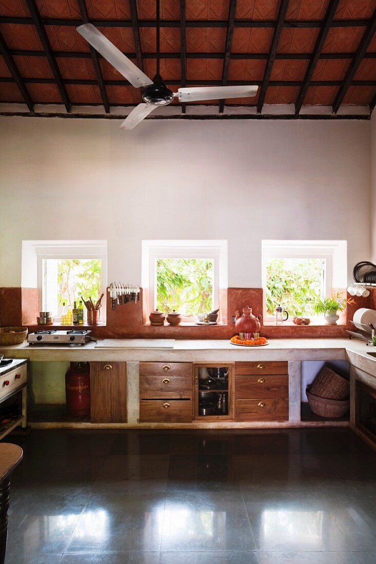 Küchenzeile mit gemauerter Arbeitsplatte am Fenster und Unterschränke