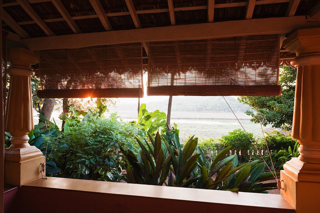 Veranda mit Kolonialsäulen vor tropischem Garten