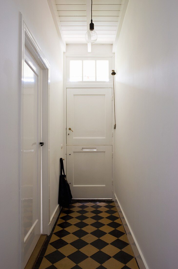 Narrow hallway with checkerboard pattern floor in a simple town home