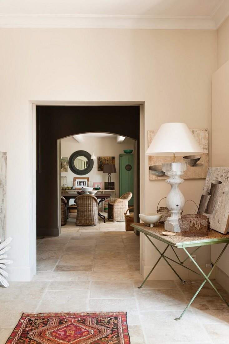 Vorraum mit Lampe auf Gartentisch und entfernter Blick in Esszimmer mit Korbstühlen