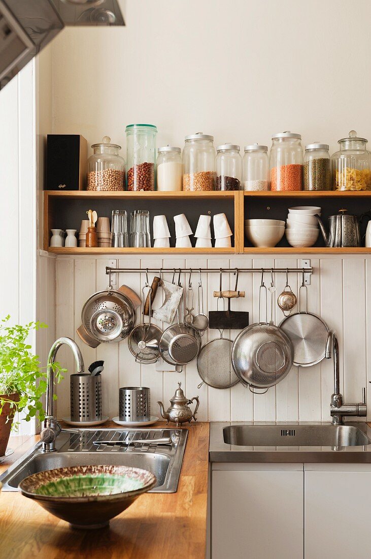 Offenes Küchenregal mit Aufbewahrungsgläsern und Geschirr über der Spüle