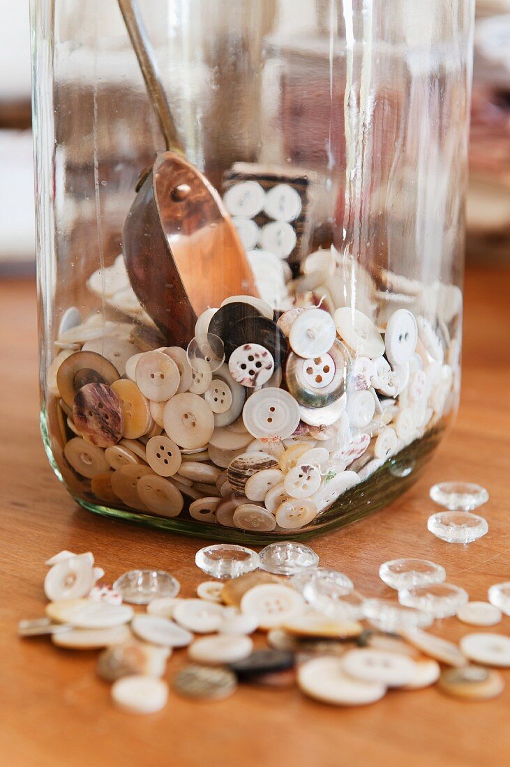 Buttons in and around a glass jar.